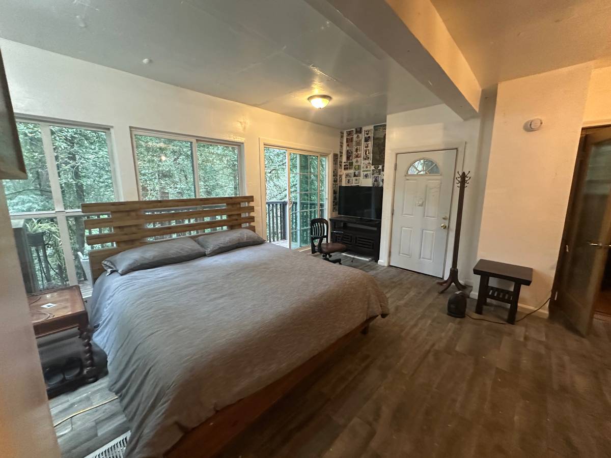 Master bedroom before editing — warmer color cast, coat rack and side table on the right wall, dim balcony exposure.