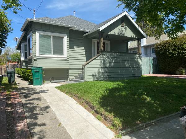 Green craftsman bungalow before editing — two trash cans on the walkway distract from the porch and front of the house.